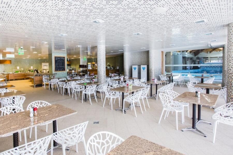 Svijetli restoran Vivae s bijelim stolicama uz staklenu stijenu prema bazenima