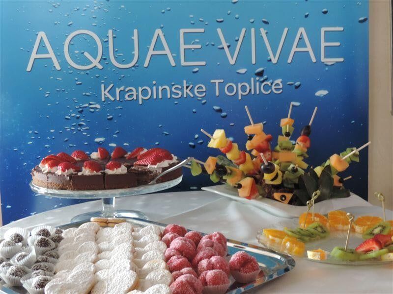 Stol sa slasticama i voćem ispred zida s natpisom Aquae Vivae